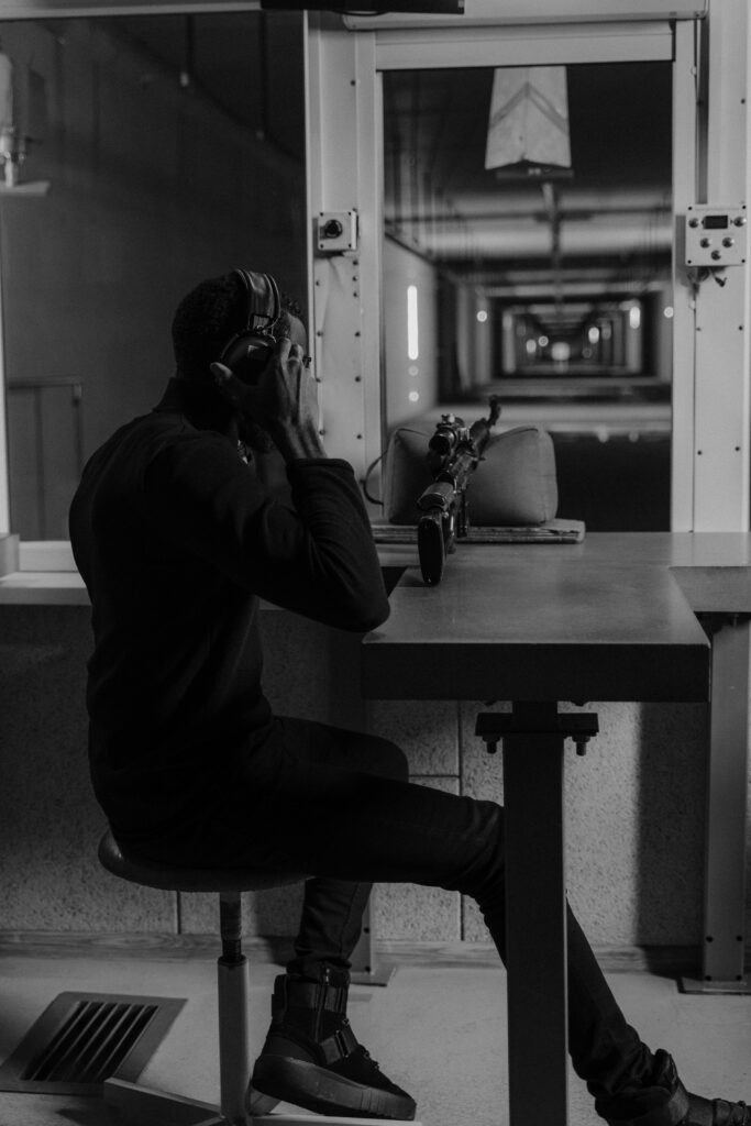 pexels-photo-6090929-6090929 Black and white image of a soldier at an indoor shooting range, wearing headphones.